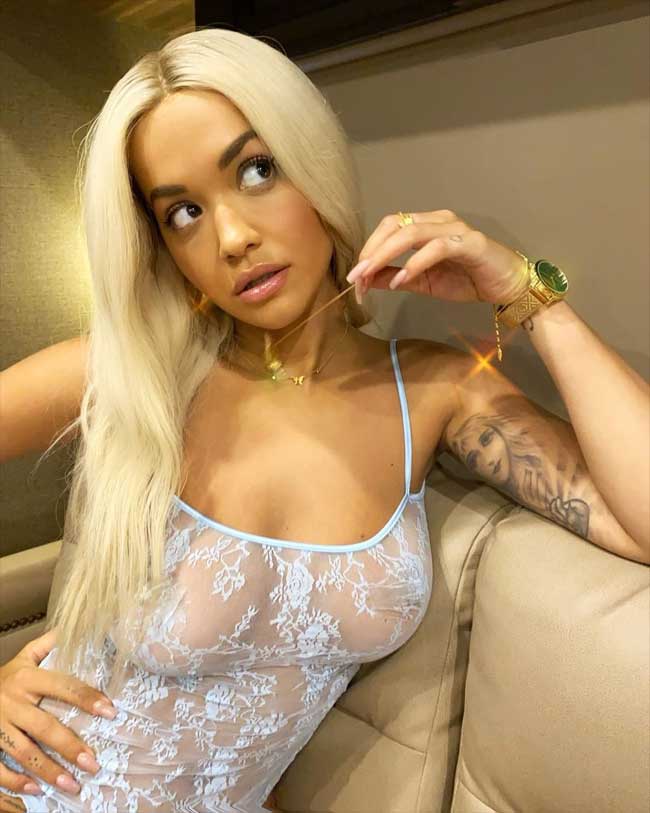 Rita Ora Big Boobs Sitting on the Couch in a Bodysuit